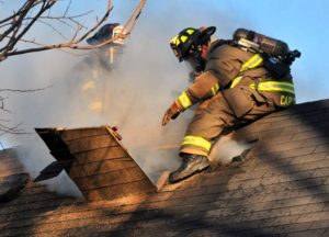 Darrell Hoemann/The News-Gazette Firefighters open a ventilation opening on the roof as they work to contain a house fire at 412 East Columbia Champaign in Champaign Saturday, January 19, 2013.