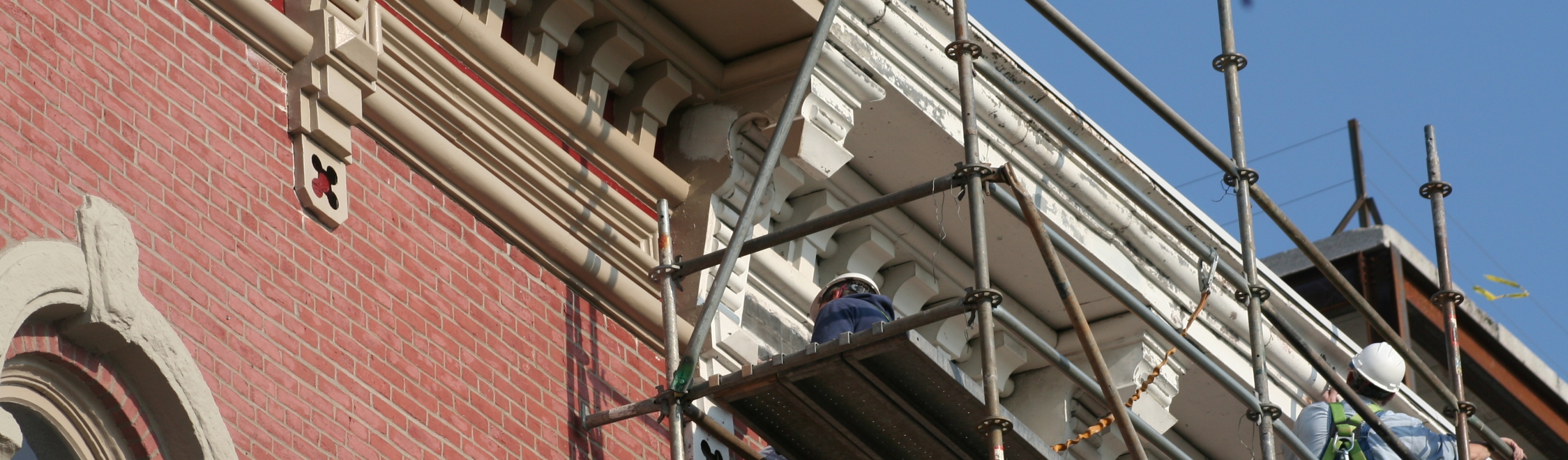 Close up shot of building being restored by workers.